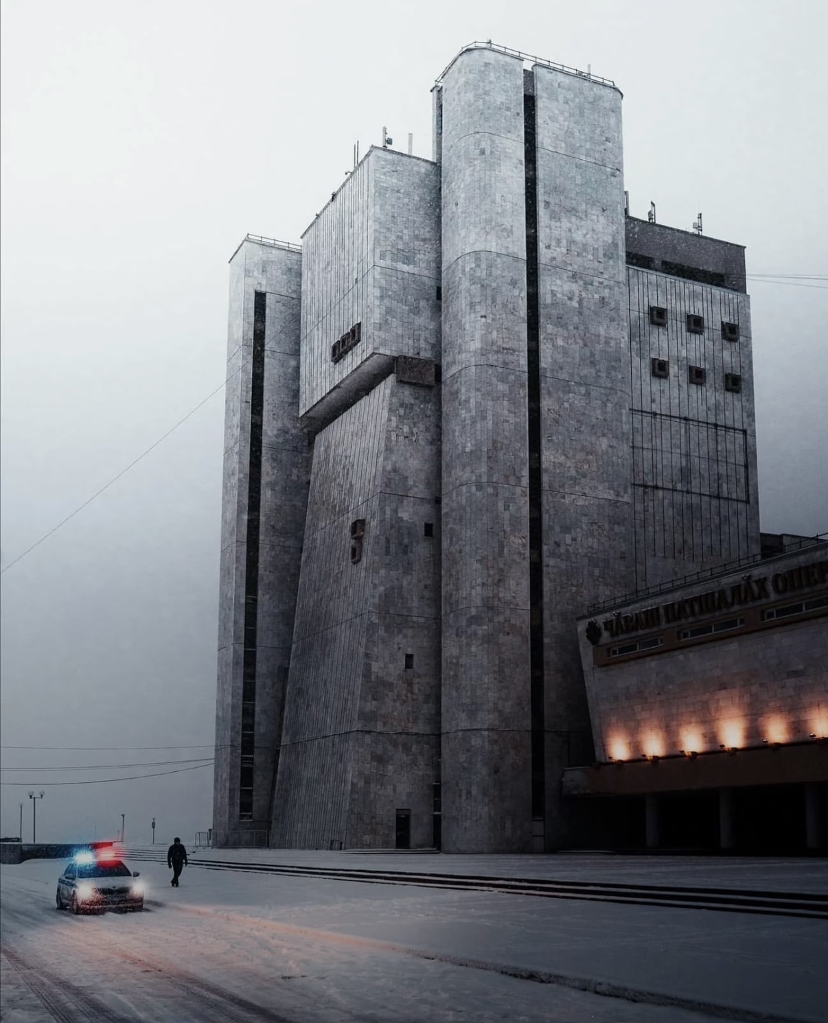 Chuvash State Opera and Ballet Theater — winter night, police car, lone figure dwarfed by concrete towers